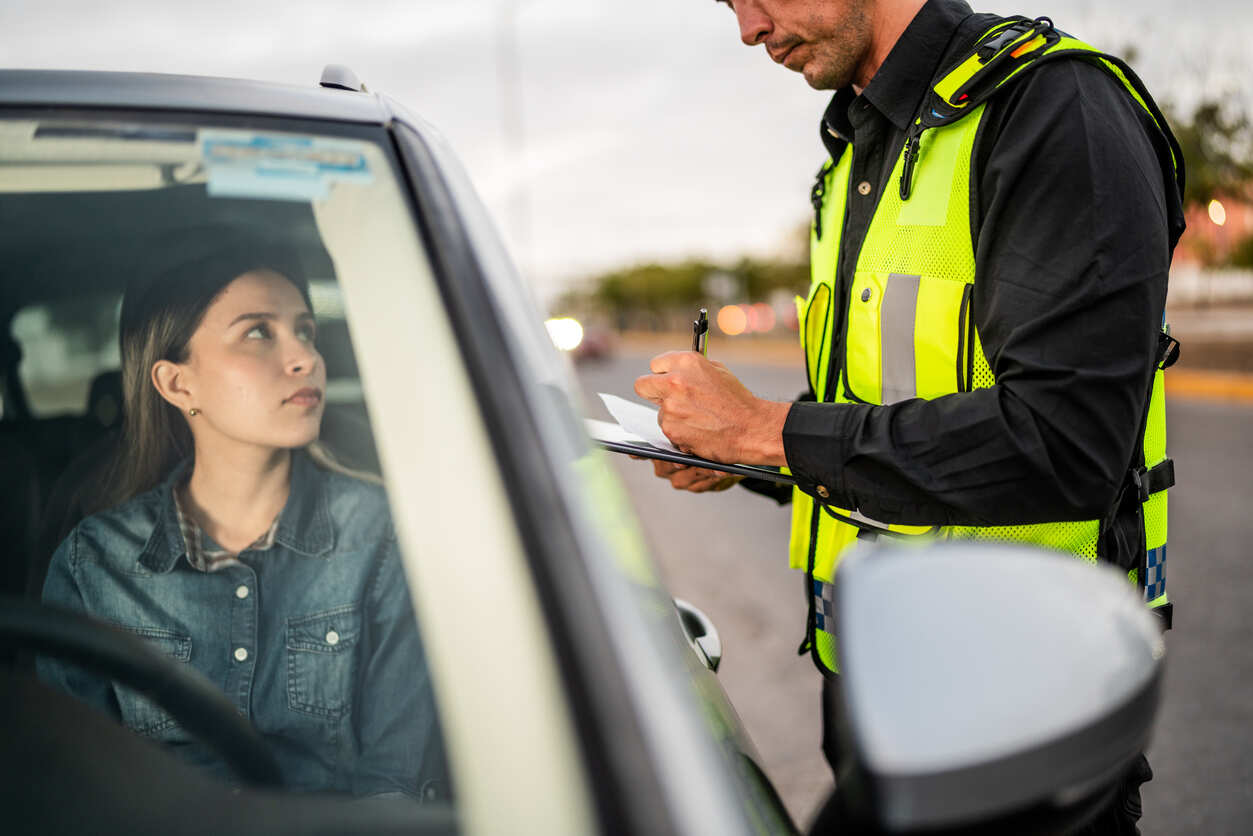 A police officer writing a ticket for a female driver, symbolizing a traffic violation and the need for a defense lawyer in Columbia, South Carolina.