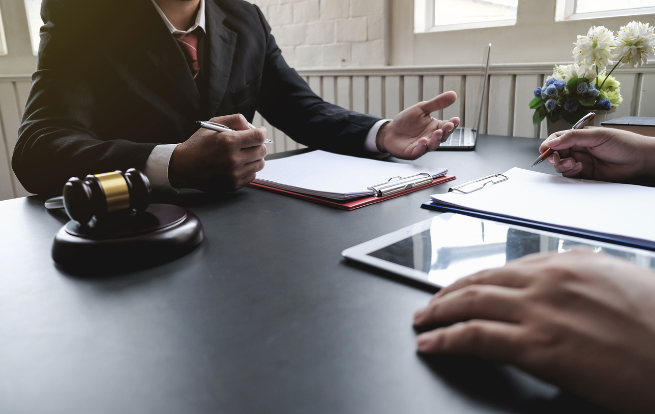 Mediation attorney consulting with client, gavel and legal documents on desk