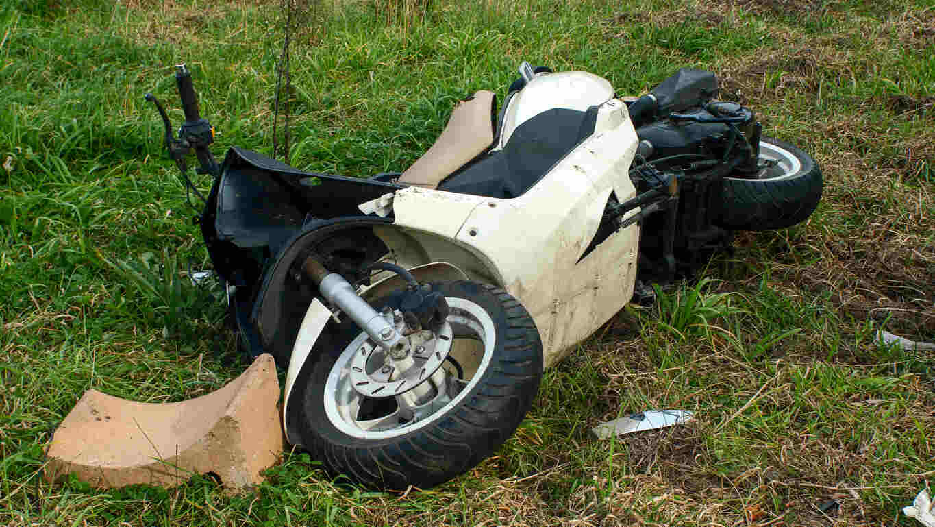 Damaged motorcycle lying on its side in a grassy area, suggesting a recent accident; relevant to motorcycle accident attorneys.